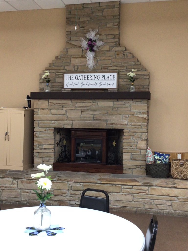 Fireplace with sign that reads The Gathering Place